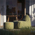 Groene outdoor poef naast een comfortabele loungestoel op een zonnig terras met gras op de voorgrond duurzaam ontwerp van sackit voor binnen en buiten