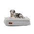 Een jonge hond rust op een lichtgrijs hondenbed van sackit met stevige stiksels en zachte bekleding voor comfortabel gebruik binnen en buiten