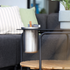 sackit ronde zwarte buitensalontafel voor buiten met teakhouten onderplank en metalen frame naast een loungesofa in een stijlvol interieur