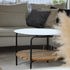 Ronde zwarte buitensalontafel met teakhouten onderplank naast een lichte loungesofa in een stijlvol interieur van sackit ontworpen voor nordisch weer