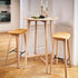 Twee hoge barkrukken van licht eikenhout met zachte leren zittingen naast een ronde bartafel in een stijlvol Scandinavisch interieur van sackit