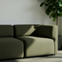 sackit driezitsbank in olijfgroene stof met afgeronde vormen in een stijlvol Scandinavisch interieur met plant en natuurlijk licht