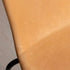 Detail van een cognackleurige leren eetkamerstoel met verfijnde dubbele stiknaad en een subtiel zichtbaar zwart onderstel, ontworpen voor comfort en duurzaamheid.