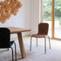 Bruine Chair no. One S1 eetkamerstoel van sackit in een licht interieur met houten eettafel grote ramen en uitzicht op een groene tuin
