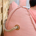 Roze Cobana zitzak van sackit met stevig touw handvat en persoon die comfortabel buiten zit bij een houten wand
