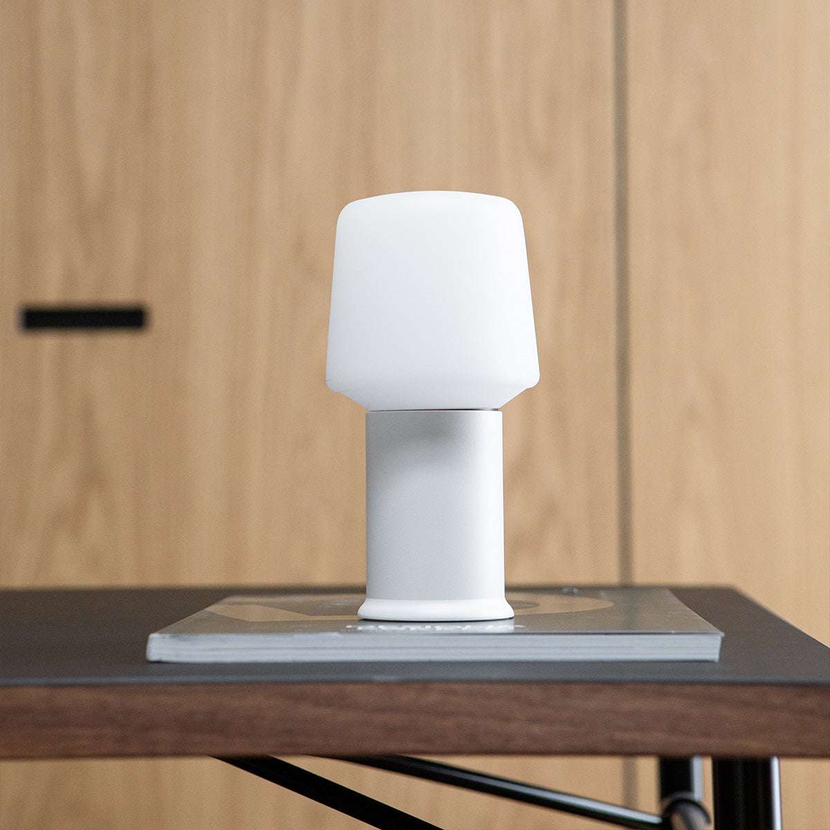 Witte draadloze tafellamp met strak Scandinavisch ontwerp op een houten tafel, passend bij de Ambience collectie van sackit voor binnen en buiten