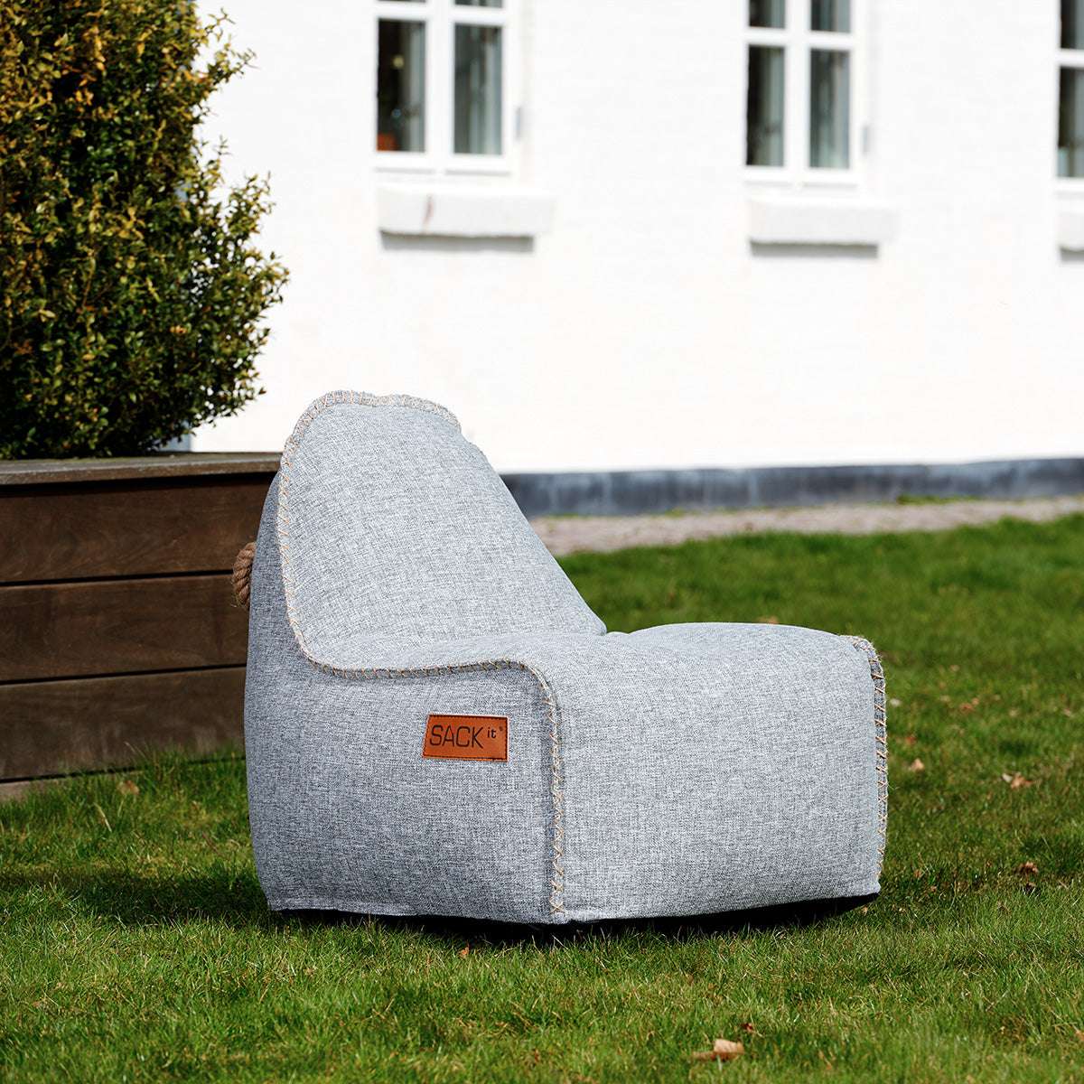 Lichtgrijze Cobana Junior zitzakstoel van sackit op het gras in de tuin met comfortabele rugleuning voor kinderen en gebruik binnen en buiten