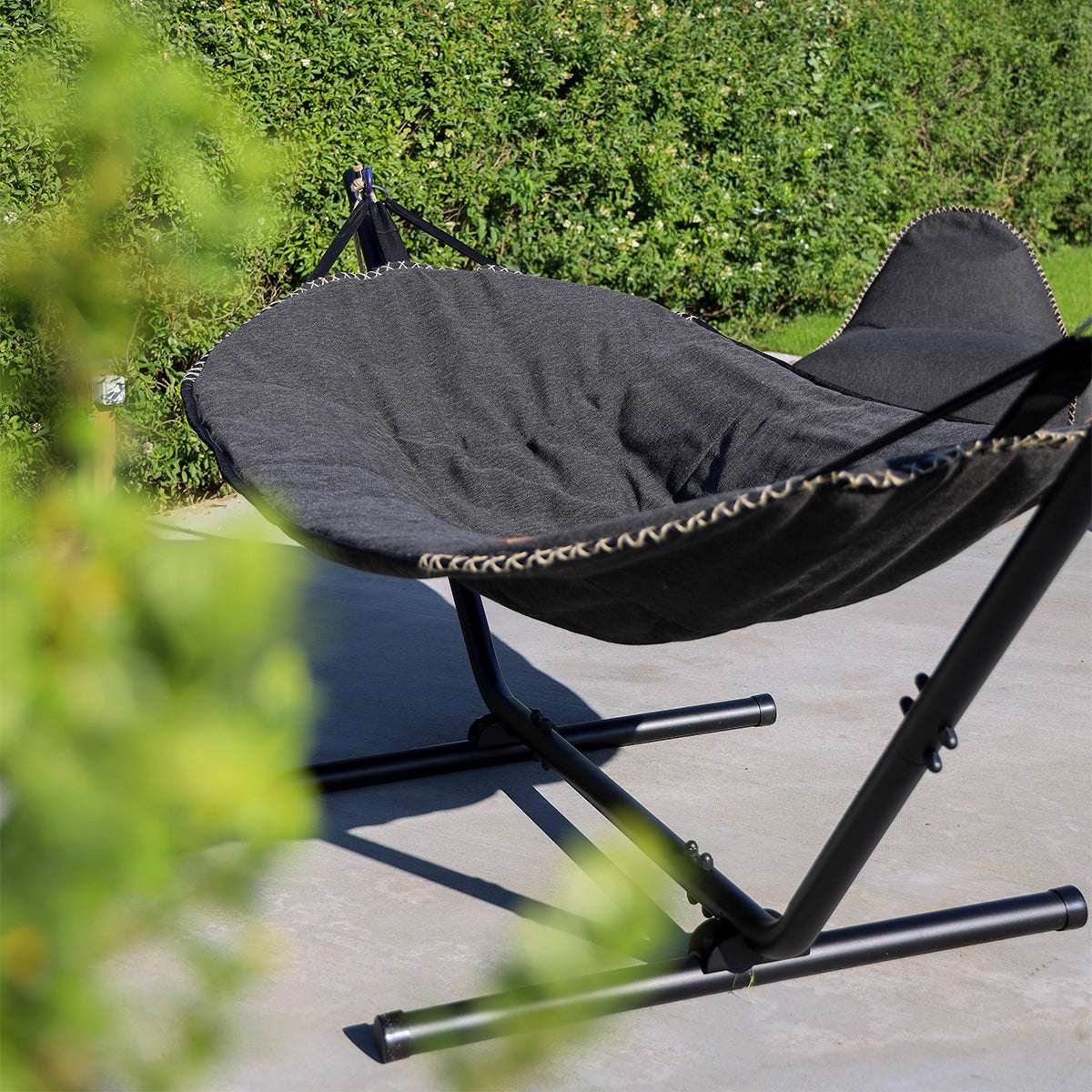 Zwarte Cobana hangmat van sackit op een stevig metalen frame in een groene tuin met comfortabel ligvlak en verstelbare hoofdsteun