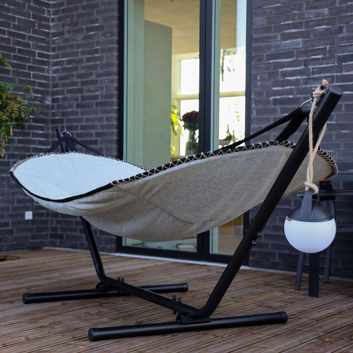 Cobana hangmat van sackit op een zwarte standaard op een houten terras met zacht ligcomfort en weerbestendig ontwerp voor buitengebruik