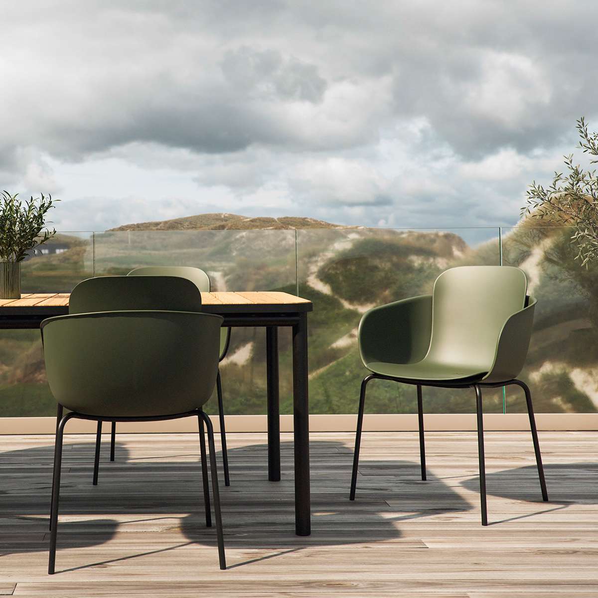 Groene buitenstoelen van sackit rond een houten tuintafel op een terras met uitzicht op heuvels en een bewolkte lucht Scandinavisch design voor buitenleven