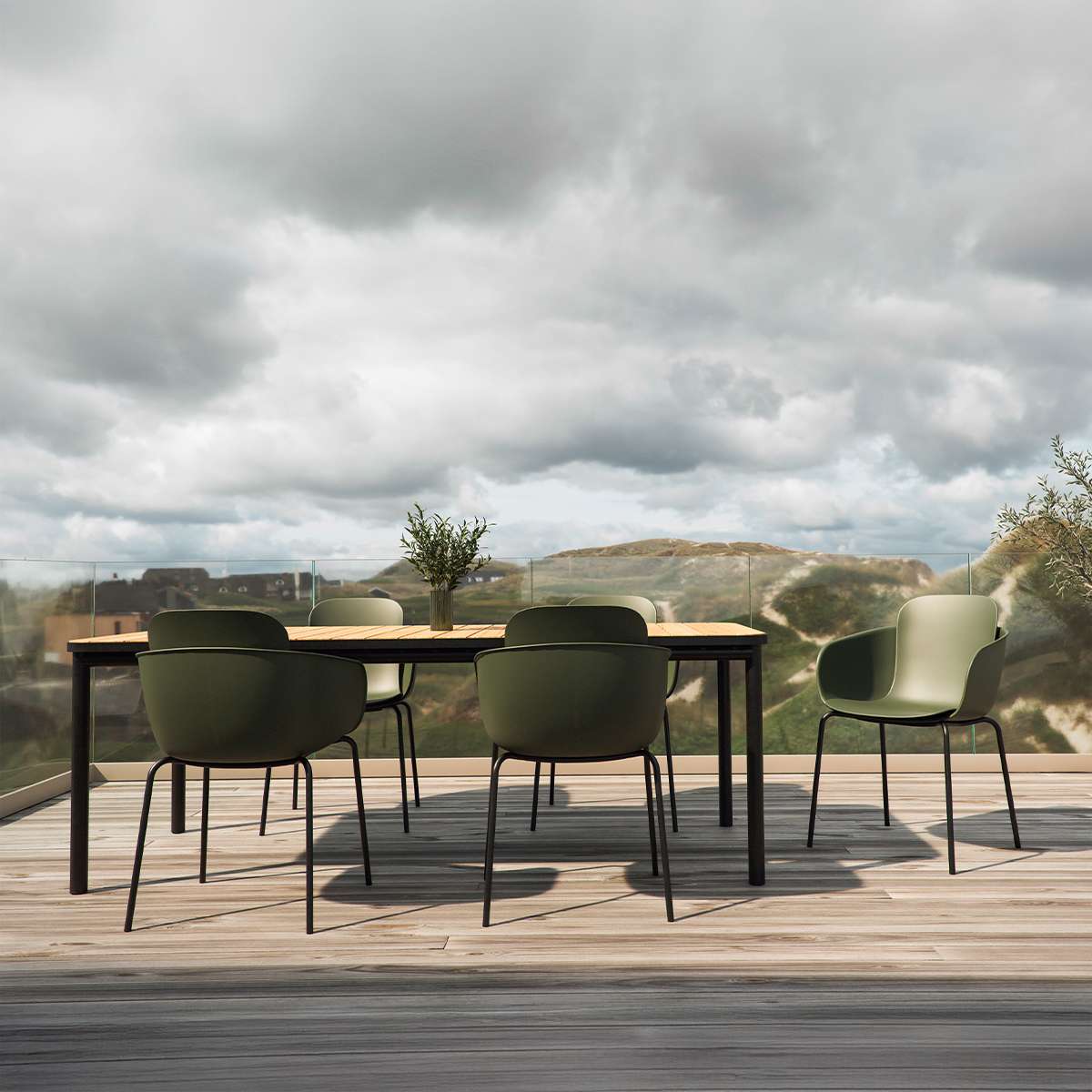 Groene tuinstoelen rond een zwart buiteneetbord op een houten terras met uitzicht op heuvels onder een bewolkte hemel van sackit