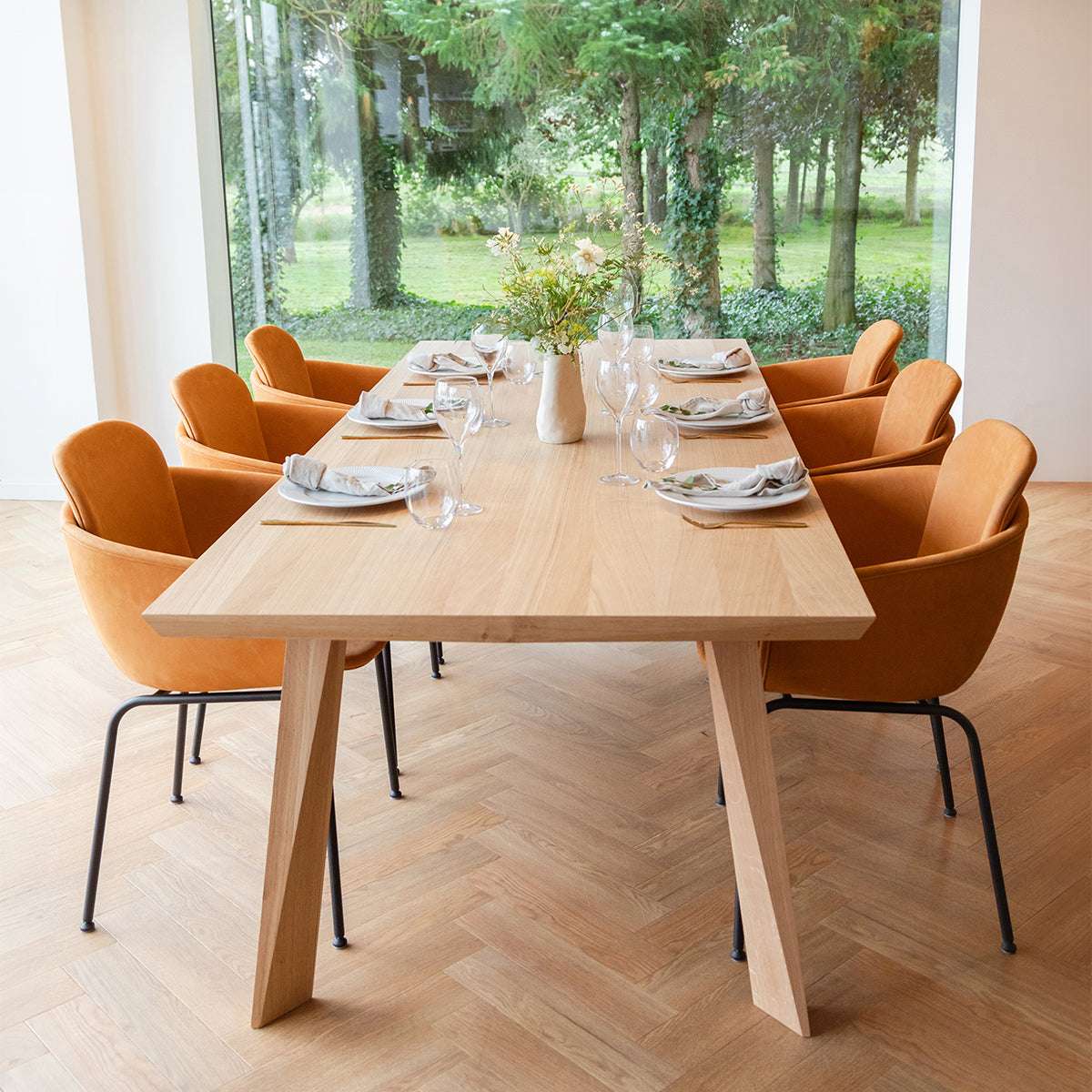 sackit eikenhouten eettafel met gefacetteerd tafelblad en zes comfortabele cognackleurige eetkamerstoelen in een lichte Scandinavische eetruimte