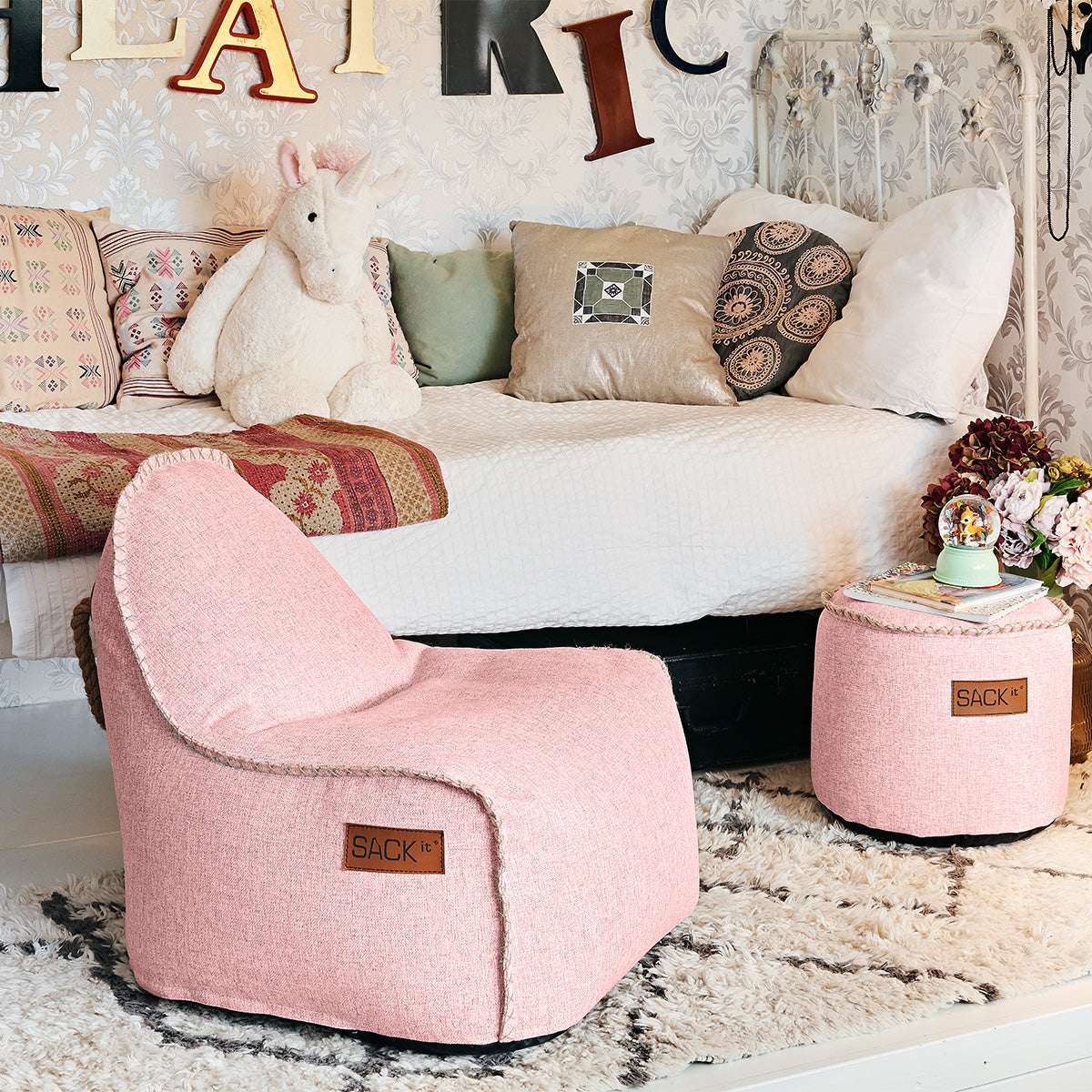Roze kinder loungestoel met bijpassende poef van sackit voor comfortabel binnengebruik in een sfeervolle woonkamer met zachte bekleding en ronde vormen