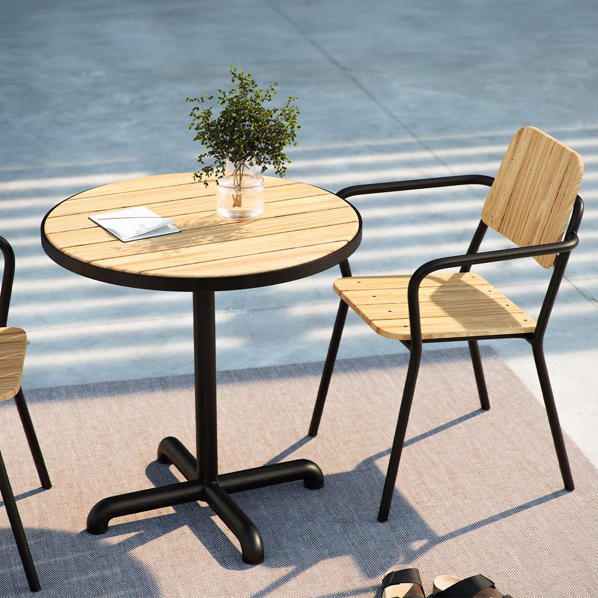 Kirra Cafe Table & 2 Kirra Patio Chair in Noir van sackit buiten bij natuurlijk licht